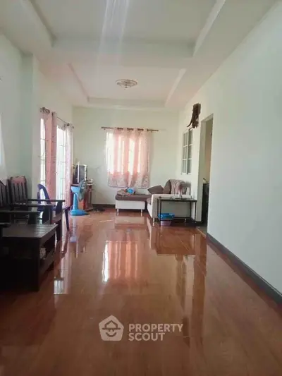 Spacious living room with polished wooden floors and cozy seating area.