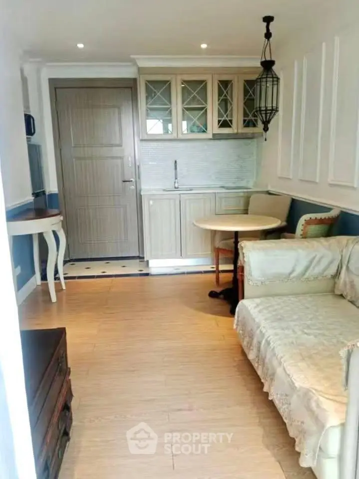 Charming compact living room with cozy seating and elegant kitchenette in modern apartment.