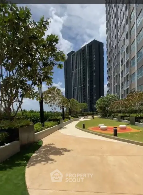 Modern high-rise buildings with landscaped garden and walking path under a clear blue sky.