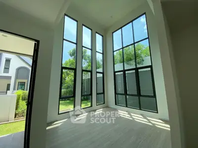 Stunning high-ceiling room with large windows and garden view in modern home