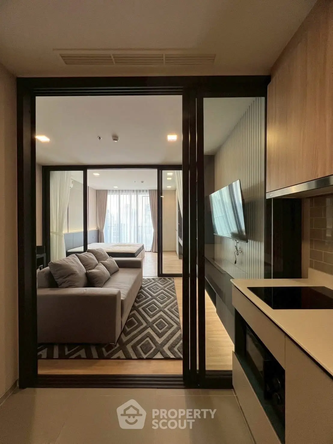 Modern living room with sleek design and open layout, featuring a cozy sofa and large TV.