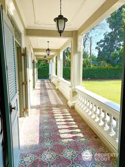 Elegant colonial-style balcony with intricate tile flooring and lush garden view