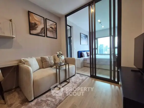 Modern living room with sliding glass doors leading to a stylish bedroom with city view.