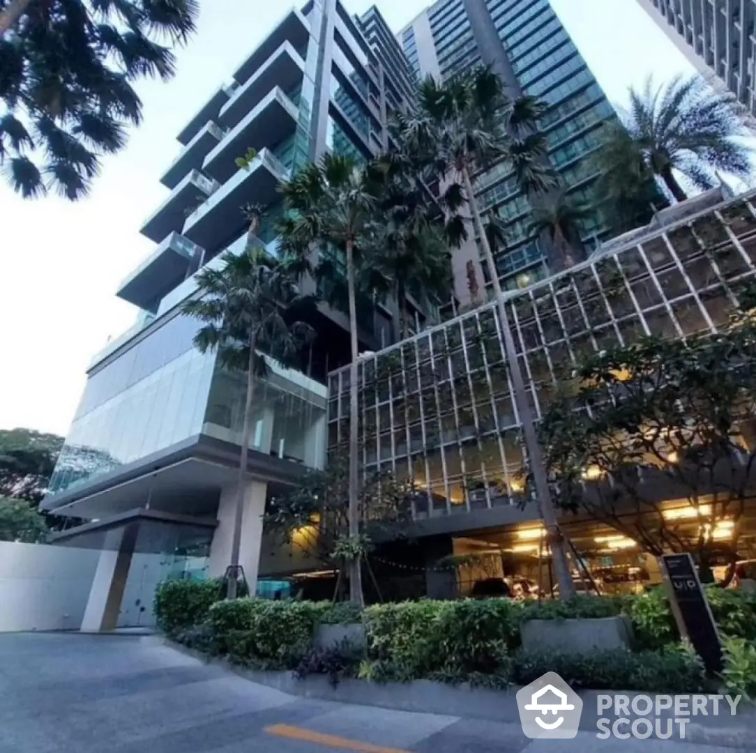 Modern high-rise building with lush greenery and glass facade in urban setting