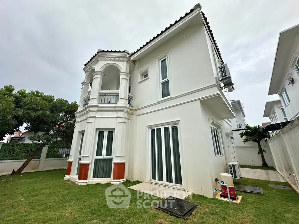 Elegant two-story white villa with lush green lawn and classic architectural design.