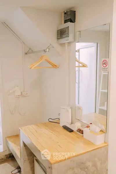 Compact hotel room with wooden desk, mirror, and hanging space.