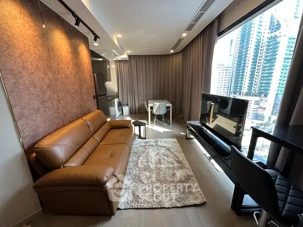 Modern living room with leather sofa, large window view, and stylish decor in urban apartment.