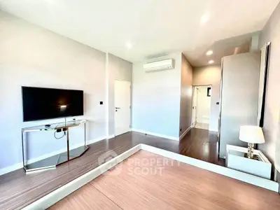 Spacious modern living room with sleek design and large TV, perfect for relaxation and entertainment.