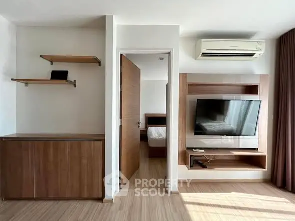 Modern living room with TV, air conditioning, and wooden shelves in a stylish apartment.