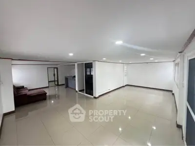 Spacious living room with modern tile flooring and ample natural light