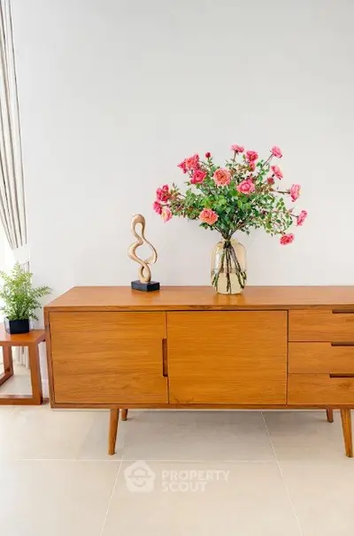 Stylish modern living room with elegant wooden sideboard and decorative floral arrangement.