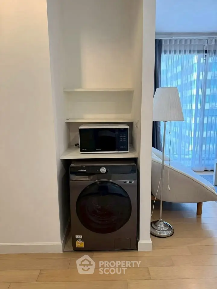Modern apartment interior with washing machine and microwave in a cozy living space.