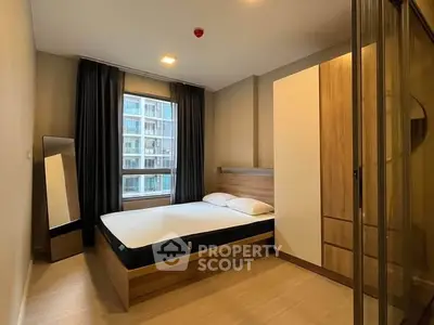 Modern bedroom with large window and wooden furniture in urban apartment.