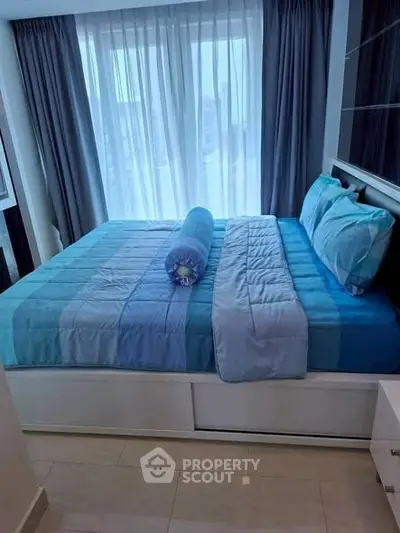 Modern bedroom with large window and stylish blue bedding in a cozy apartment.