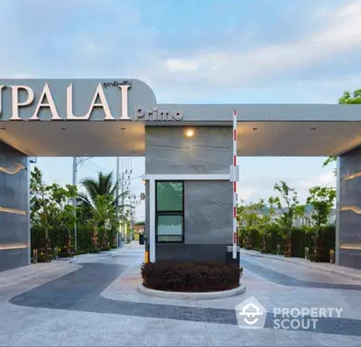 Elegant entrance of a modern residential complex with lush greenery and sleek design.