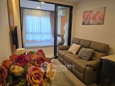 Cozy living room with modern decor and view into a stylish bedroom through glass doors.