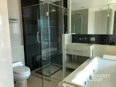 Luxurious bathroom with a large jacuzzi tub, glass-enclosed shower, and modern vanity set against a backdrop of elegant black marble.