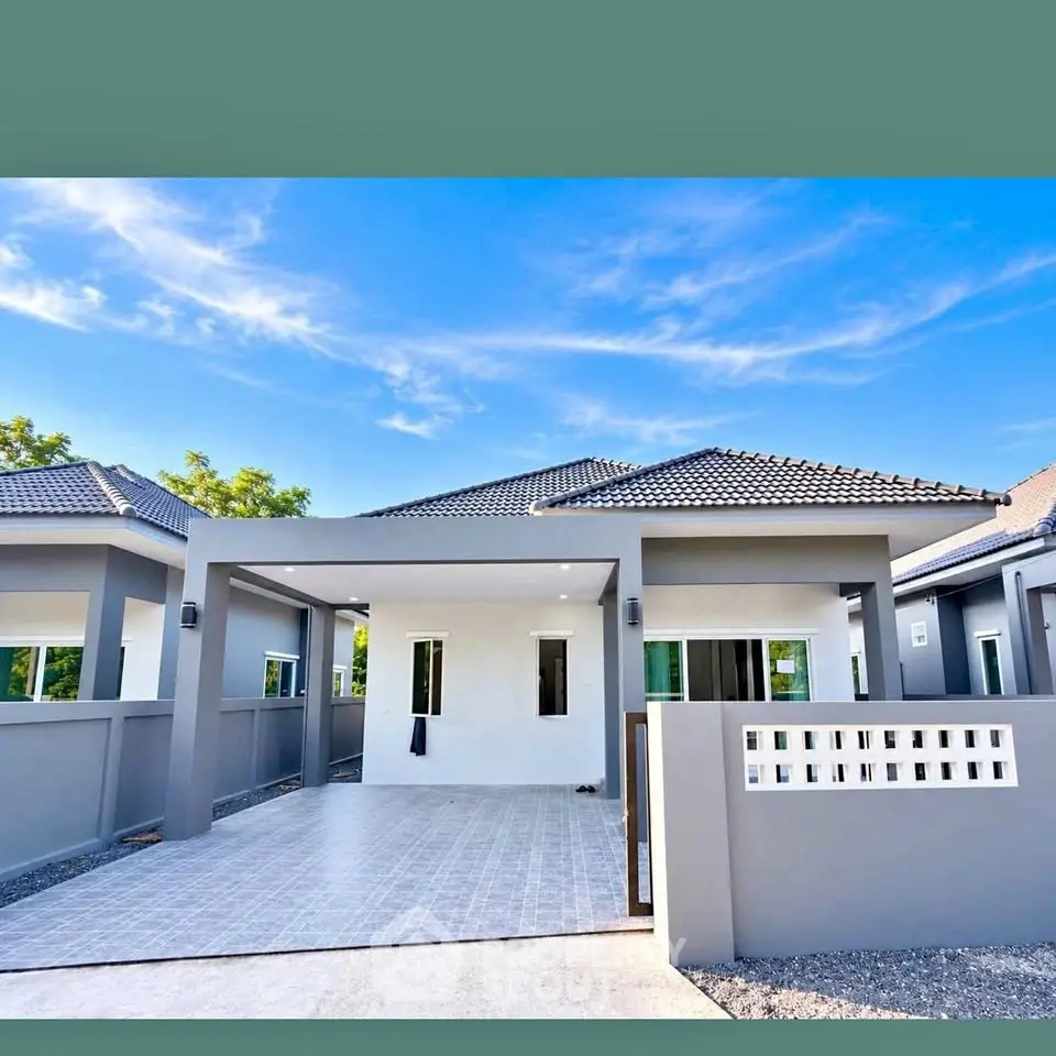 Modern single-story house with sleek design and spacious driveway under clear blue sky.