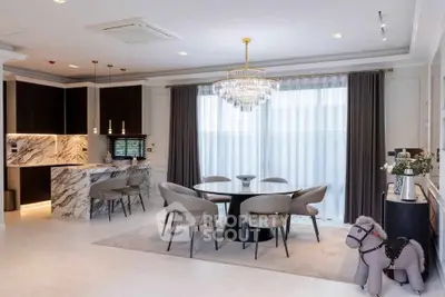 Luxurious open-plan living and dining area with elegant marble accents and modern chandelier.