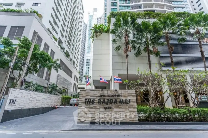 Luxurious high-rise condo entrance with lush greenery and modern architecture in prime city location.