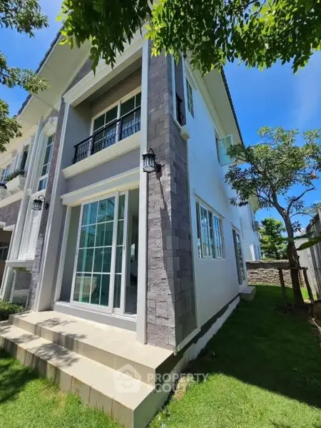 Modern two-story house with large windows and lush green lawn