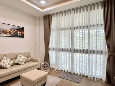 Elegant living room with large windows and stylish curtains, featuring a cozy sofa and modern decor.