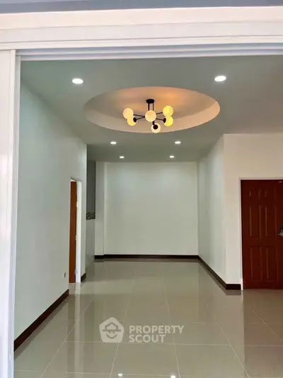 Spacious modern living room with elegant ceiling light fixture and glossy tiled floor.