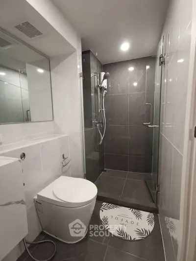 Modern bathroom with sleek glass shower and elegant fixtures in contemporary apartment.