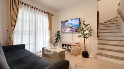 Modern living room with stylish decor and staircase, featuring a wall-mounted TV and elegant curtains.