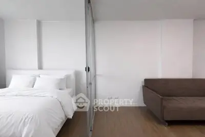 Modern bedroom with sliding glass partition and cozy sofa in minimalist design.