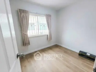 Bright empty bedroom with wooden flooring and large window