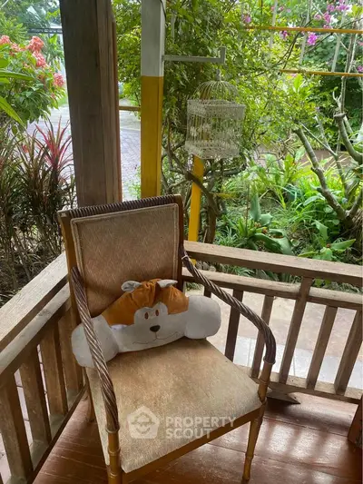 Charming garden view from a cozy wooden balcony with a cute cushion on a chair.