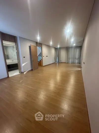 Spacious empty living room with wooden flooring and modern lighting