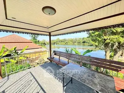 Charming balcony with serene lake view and elegant wooden bench.