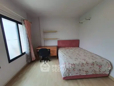 Cozy bedroom with floral bedspread and study desk, perfect for relaxation and productivity.