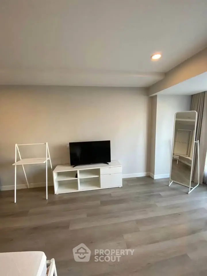 Spacious modern living room with sleek wooden flooring and minimalist furniture, perfect for contemporary living.