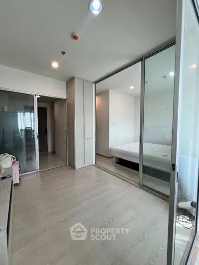 Modern bedroom with glass partition and wooden flooring in a stylish apartment.