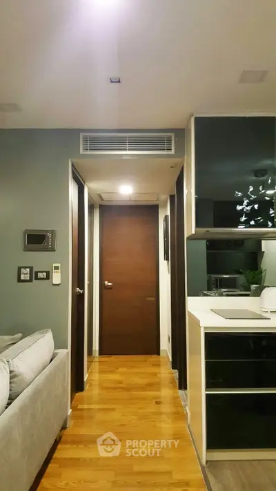 Modern apartment interior with sleek kitchen and cozy living area, featuring stylish decor and wooden flooring.