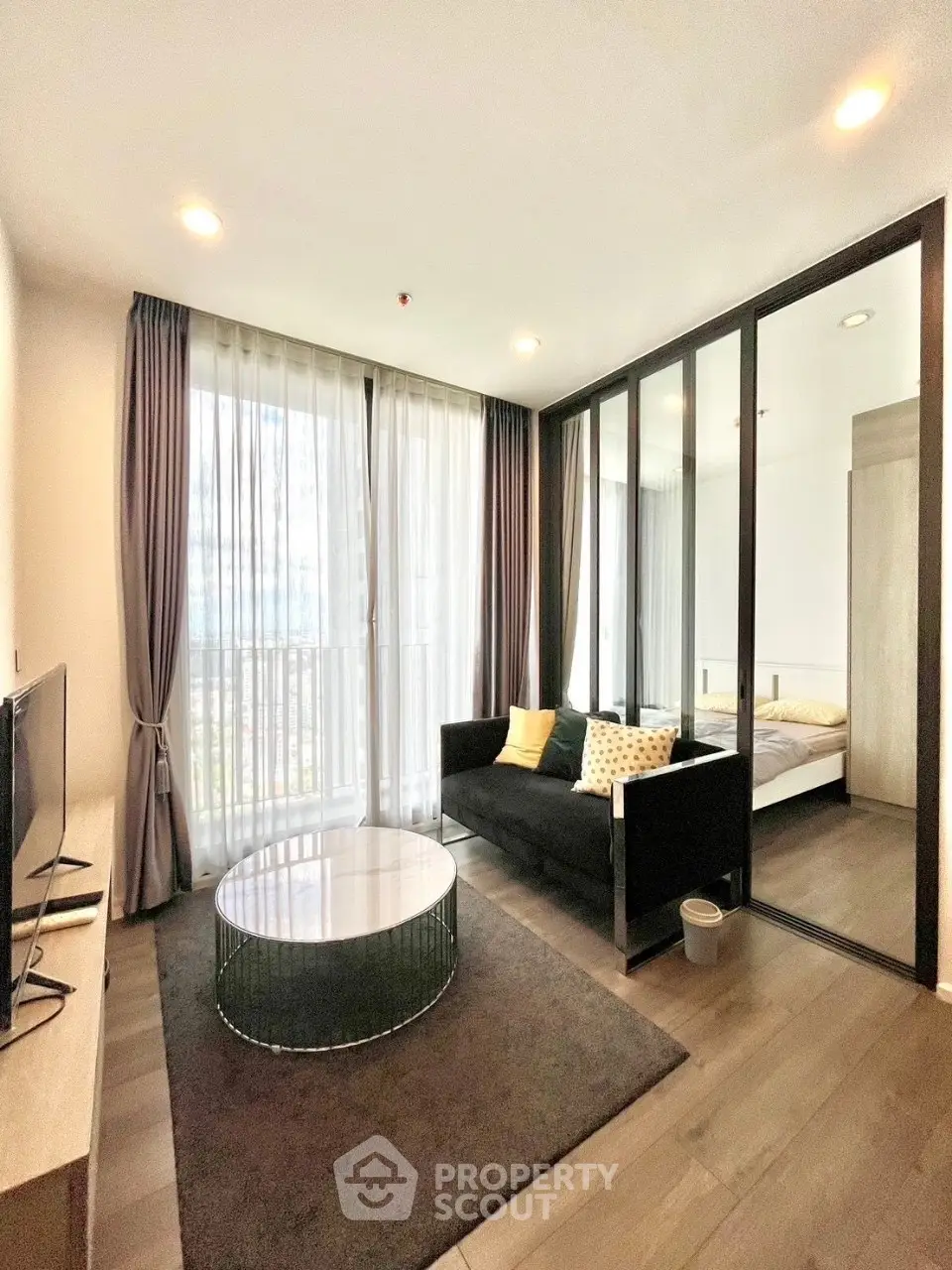 Modern living room with glass partition and cozy bedroom view