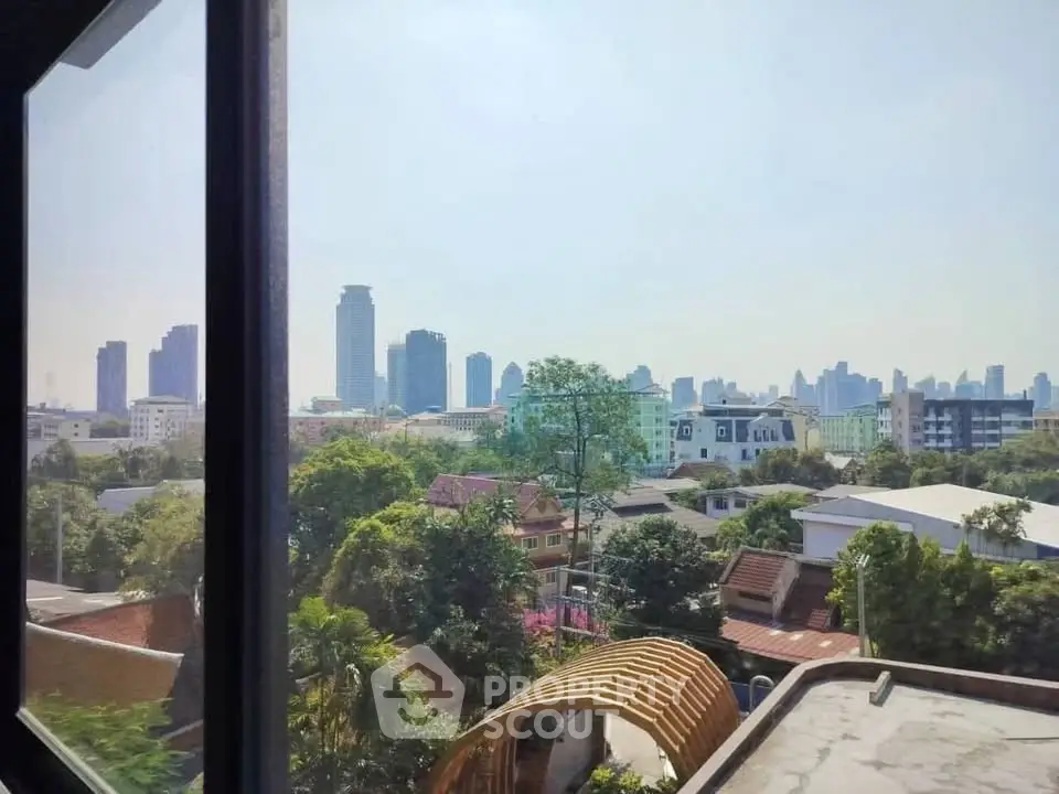 Stunning cityscape view from a high-rise window showcasing urban skyline and lush greenery.