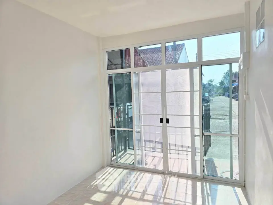 Bright room with large sliding glass doors opening to a sunny street view, perfect for natural light lovers.