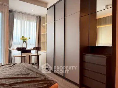 Modern bedroom with sleek storage and cozy seating area by the window.