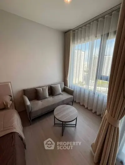 Cozy bedroom with a sofa and large window offering city views, perfect for relaxation.