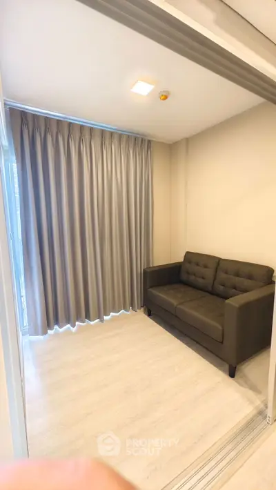 Cozy small living room with modern sofa and elegant curtains, perfect for urban living.