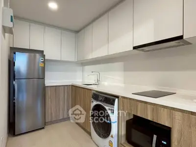 Modern kitchen with sleek cabinets, washing machine, and stainless steel fridge