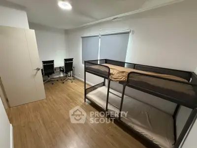 Modern bedroom with bunk bed and study area, featuring sleek wooden flooring and minimalist design.