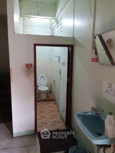 Compact bathroom with blue sink and tiled floor, featuring a basic toilet setup.
