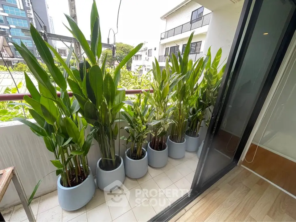 Charming balcony with lush potted plants and sliding glass door, perfect for relaxation.