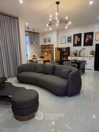 Modern living room with stylish curved sofa and elegant lighting, featuring open layout and contemporary decor.