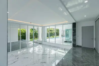 Luxurious modern interior with marble flooring and glass walls overlooking a serene garden and pool.